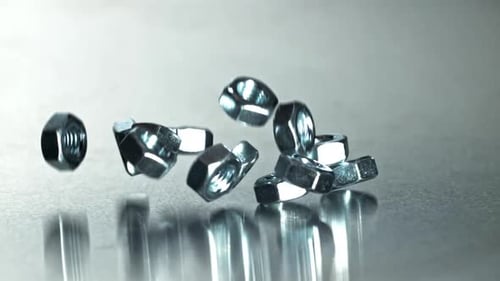 Closeup of Chrome Nuts Hitting Reflective Table During Product Testing Filmed on a Highspeed Camera