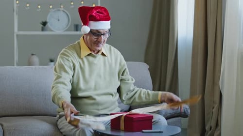 Joyful Senior Man Opening Christmas Gift at Home