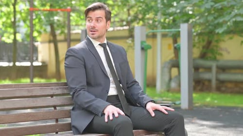 Man in Suit Sitting on Park Bench Checks Watch
