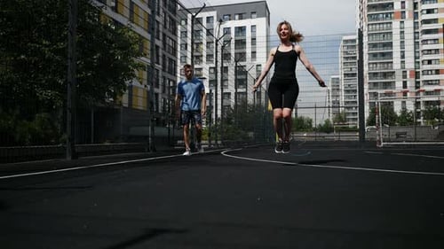 A Girl Jumps on a Basketball Court The Coach Observes the Student's Progress Slow Motion Wide Shot
