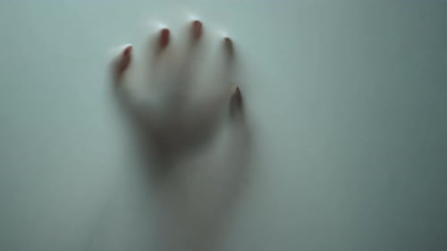 Macro Female Hand Shadow Sliding Down On Glass Surface In Studio. Mystical Horror Element With Bl...
