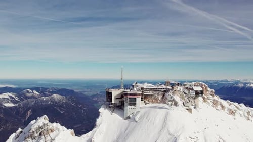 vue aérienne orbitale du sommet d'une montagne enneigée avec une vallée verdoyante en contrebas et des chaînes de montagnes dans le bac
