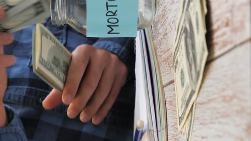 Person Divides Money Into Jars For Mortgage, Taxes