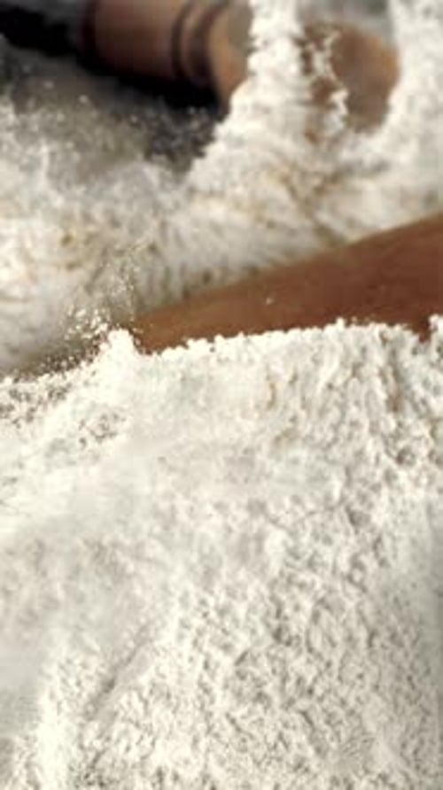 Super Slow Motion Wooden Rolling Pin Falls in a Pile of Flour on the Table Filmed on a Highspeed