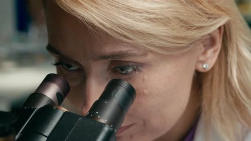 Woman Scientist Looking Into Microscope in Lab