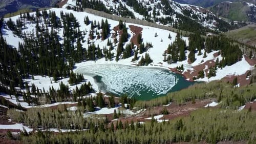 Extreme wide drone shot of Desolation Lake in Utah’s Big Cottonwood Canyon. The camera rotates aroun