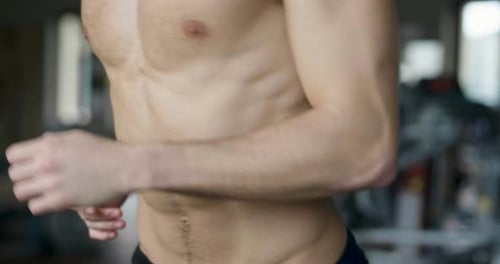 A guy in the gym to stay fit and have defined muscles or lose weight runs on the treadmill with a