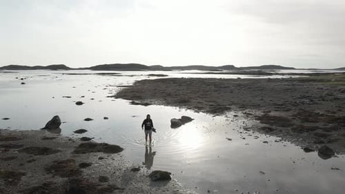 Aerial View Of A Woman Walking Barefoot On Shallow Water During Low Tide In The Sea.