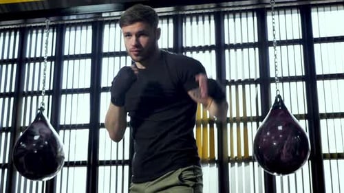 Male Boxer Shadowboxing in Gym with Water Bags