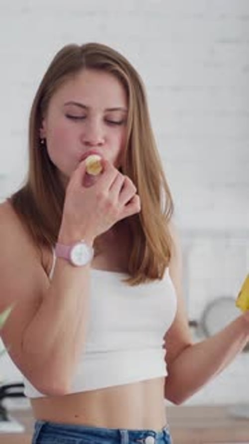 Woman Eats Banana Slice in Bright Indoor Kitchen
