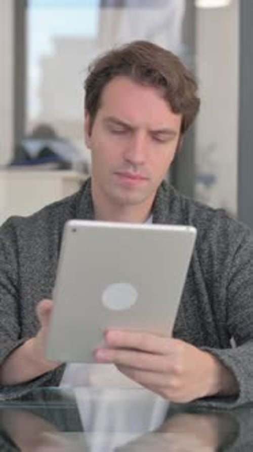 Man Browsing Content on a Tablet Device Indoors