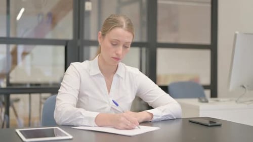 Mature Business Woman Writing a Letter in Office