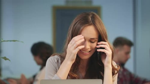 Woman Talking on Phone at Desk in Office