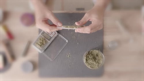 Concept stoned caucasian person rolling a joint at home, top down view
