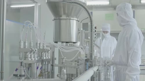 Scientists or medicine workers in protective gear managing production line at a