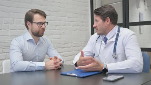 Doctor Consults With Patient at Office Table