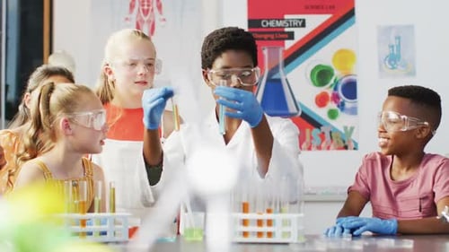 Diverse female teacher and happy schoolchildren having science class in school lab