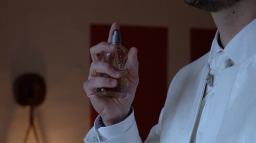 Elegant Man in White Suit Sprays on Cologne