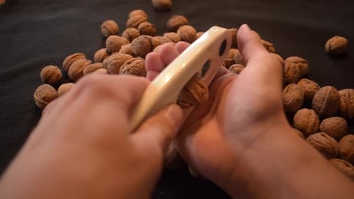 Young man is cracking some fresh dried walnuts . Healthy food. Christmas is coming.