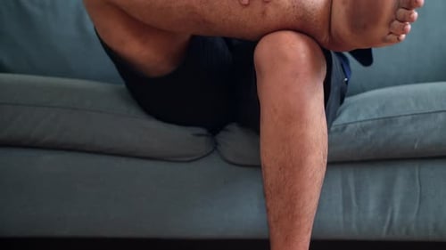 Close Up Of Young Man Massaging Swollen Leg With Hands To Relieve Discomfort