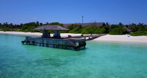 Two men in shade of covered jetty on tropical Hanimaadhoo island, aerial jib