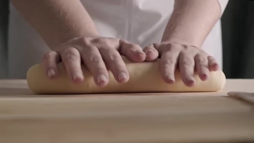 Hands Kneading Dough on Wooden Table