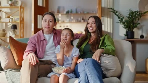 Happy family sitting on sofa eating popcorn