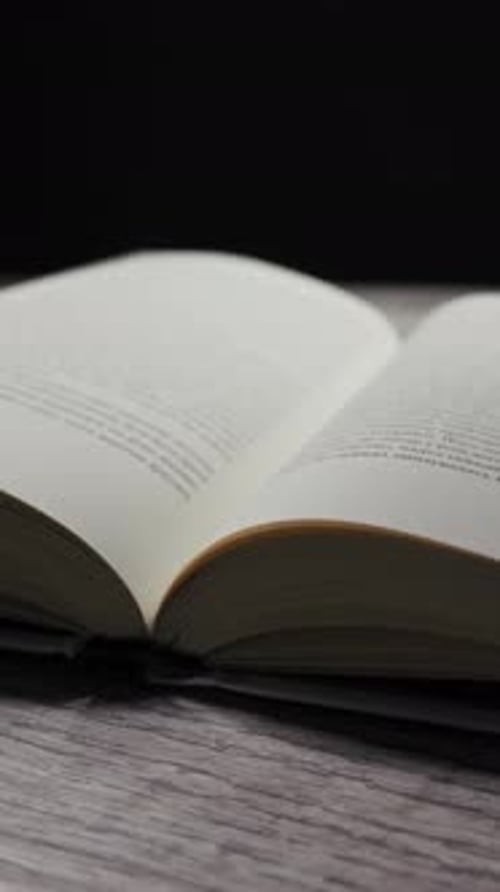 Book Page Turning on Wooden Table, close-up