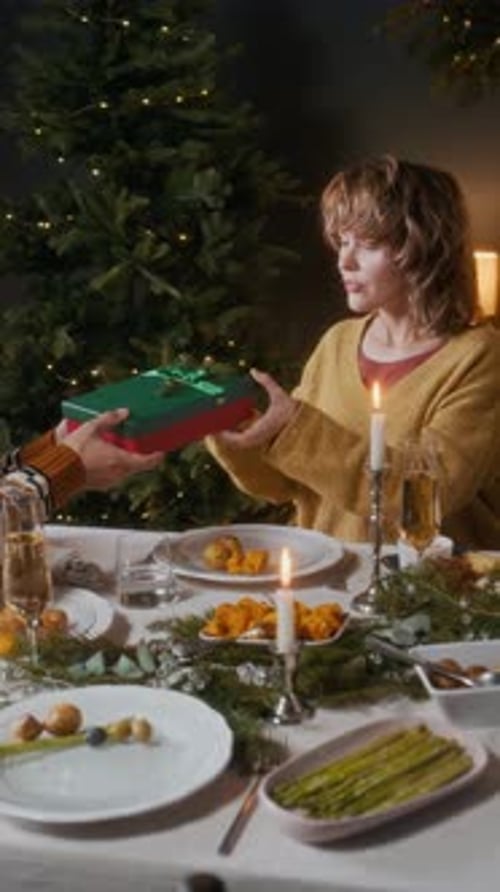 Woman Receiving Christmas Gift with Excitement at Christmas Dinner