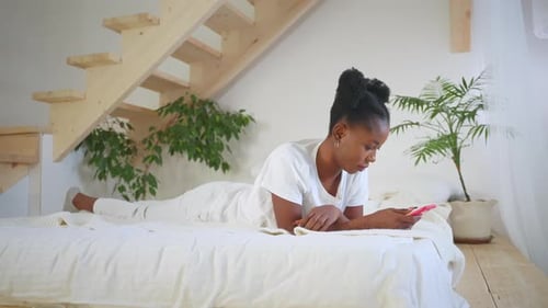 African Woman with Smartphone in Bedroom