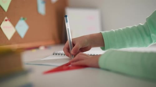 Child Drawing Line with Ruler on Notebook