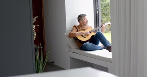 Man Playing Guitar in Sunlit Window Nook