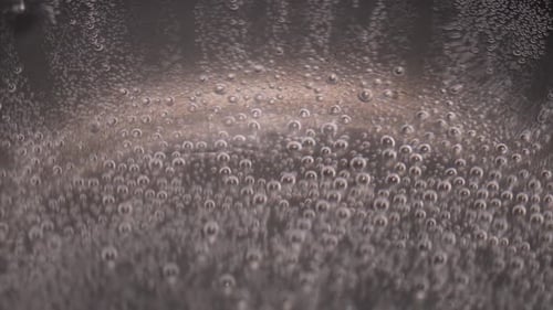 The image is of a blurry water boiling, hazy surface with many small bubbles scattered throughout.