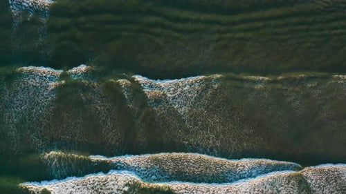 Golden Hour Aerial of Waves Crashing Softly, with the Drone Flying Along Their Path From Above