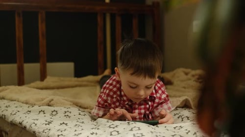 Child Lying on Bed Using Smartphone Indoors