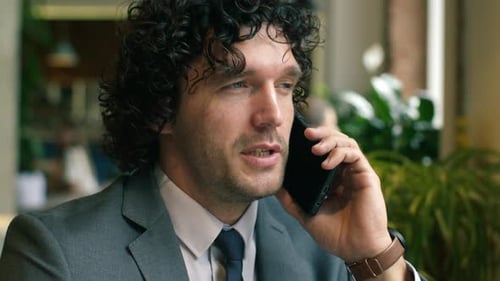 Professional Businessman Speaking during Phone Call in Modern Cafe