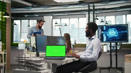 Programmeur de bureau en démarrage utilisant un ordinateur portable à écran vert pour développer des modèles d'IA