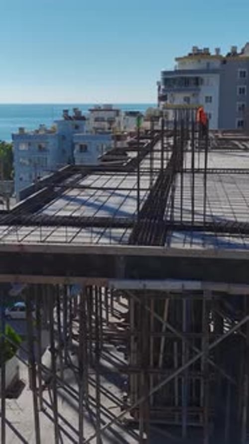 Vertical Video Aerial View of a Construction Site With Workers Installing Framework and Using Heavy
