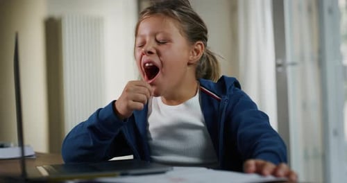 Tired Child Yawns in front of Laptop