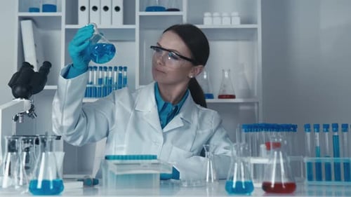 Scientist Examines Blue Liquid in Flask in Lab