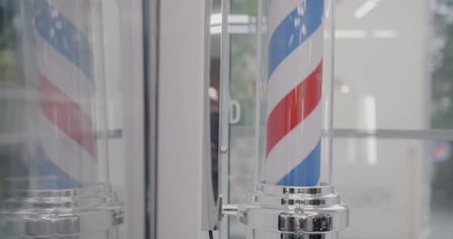 Closeup do poste de barbeiro girando contra o fundo da parede de vidro da barbearia
