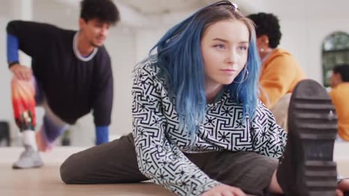 Caucasian female dancer stretching with diverse colleagues in dance studio, slow motion