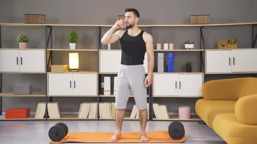 Man Drinks Water After Workout in Living Room