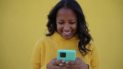 Woman Using Mobile Phone Against Yellow Background