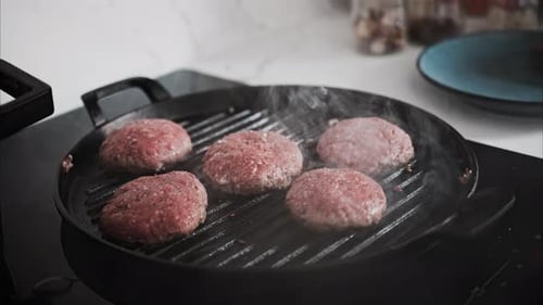 Burger patties being cooked on a grill pan