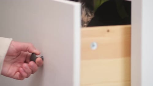 A woman's hand opens a drawer, close-up. Cabinet drawer