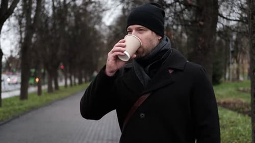 Pensive Hipster Drinking Coffee in the Urban Street Handsome Man Wearing Black Coat Brown Leather
