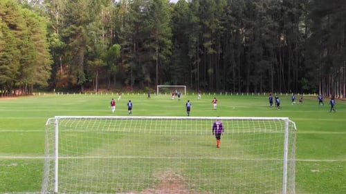 Zoom in from behind the goal duringg a soccer match