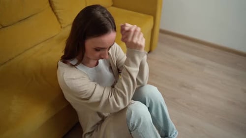 Woman Sitting on Floor Massaging Head