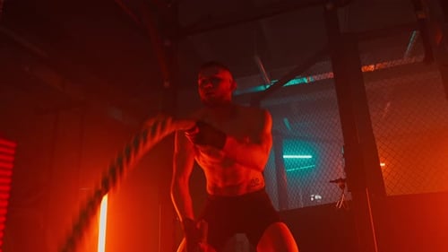 Muscular Man Exercising With Battle Ropes in Gym